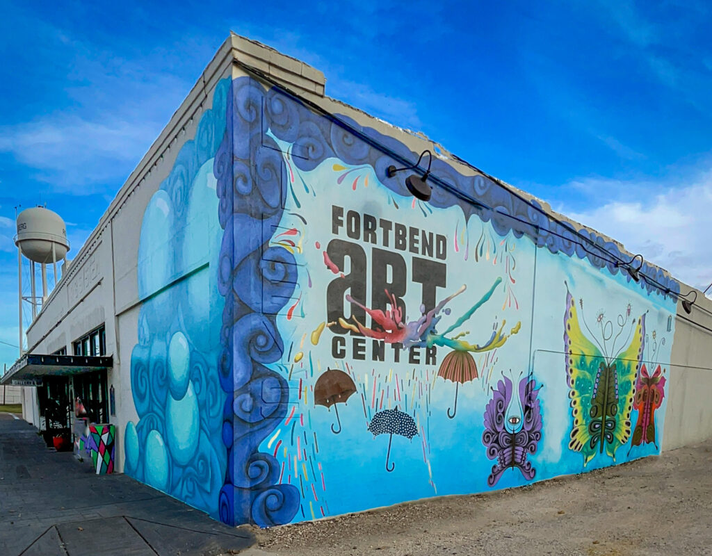 New Art Center mural with blue swirls, umbrellas and butterflies. Mural by Cisco and photo by Photos by Don.